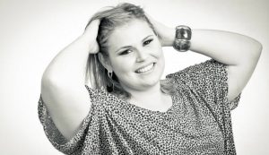 Close up of a Blonde Plus size woman, a model. The woman has her hands in the hair. In black and white.