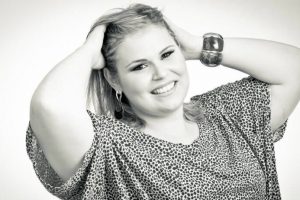 Close up of a Blonde Plus size woman, a model. The woman has her hands in the hair. In black and white.
